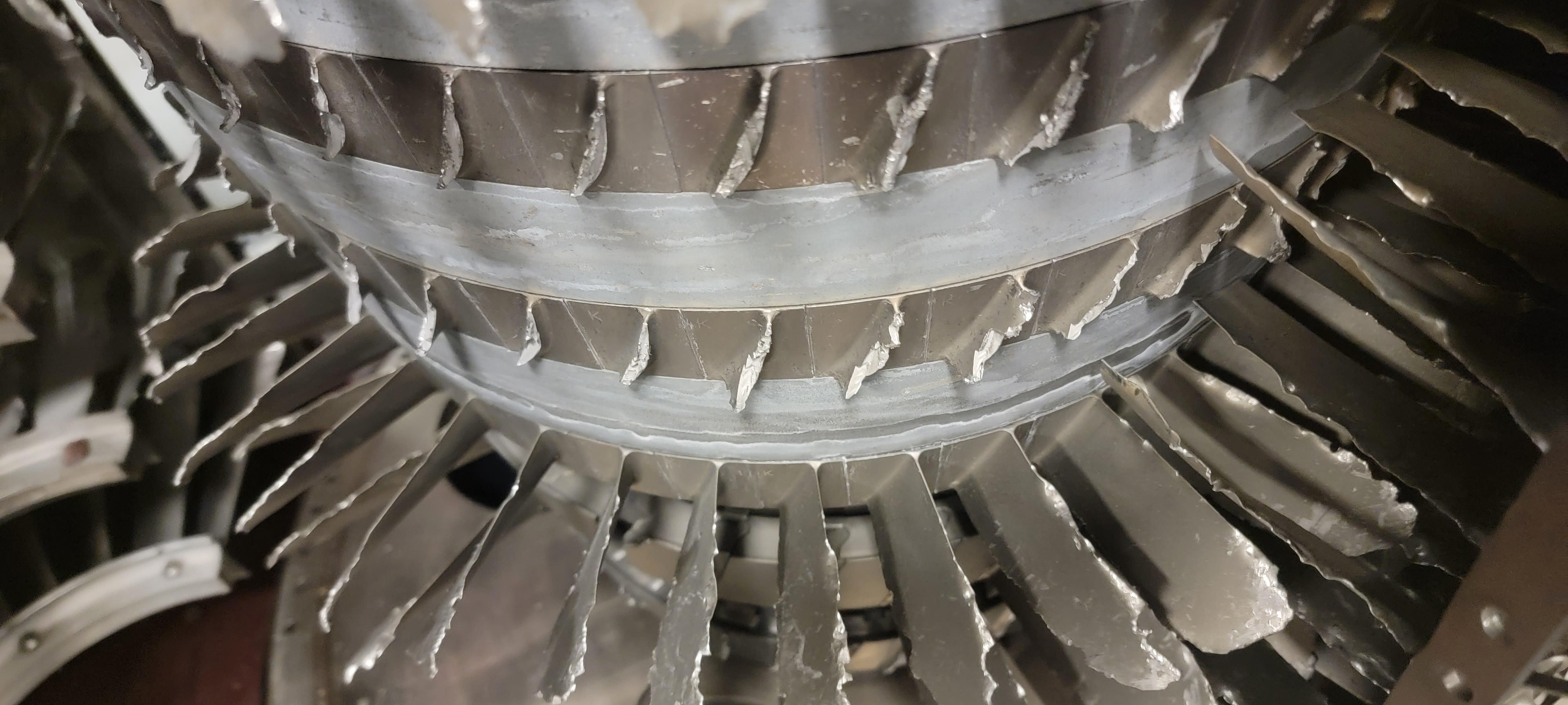 Close-up of compressor blades with torn, jagged edges across several stages